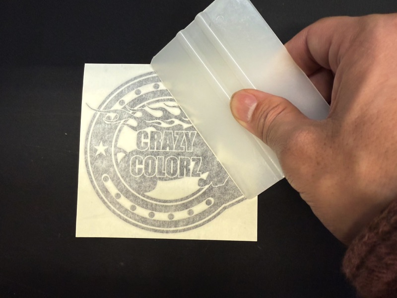 デカールステッカーインストールのスキージで上から圧着する様子
