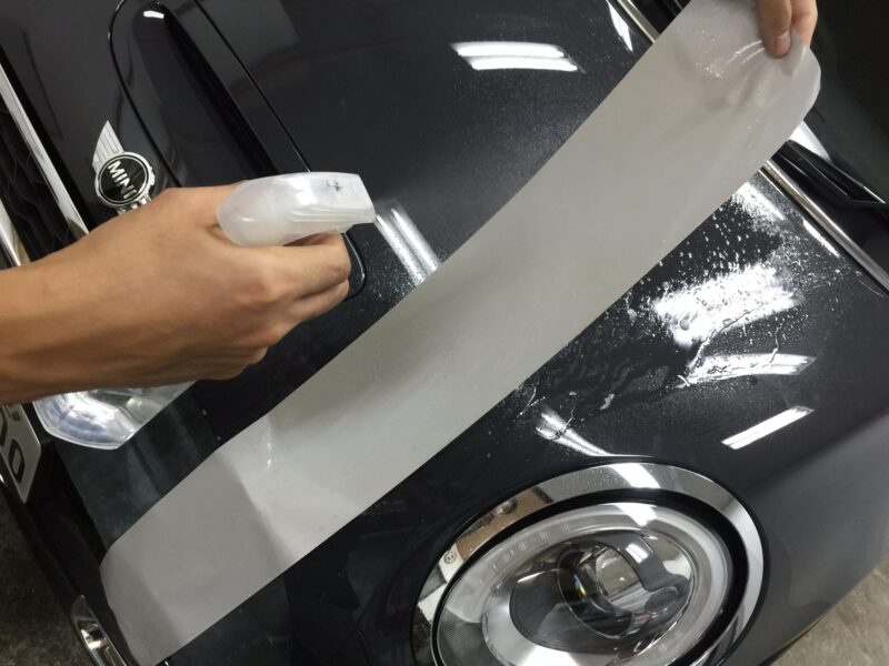 MINI R56へのストライプ施工時デカール側にも水溶液を散布している様子
