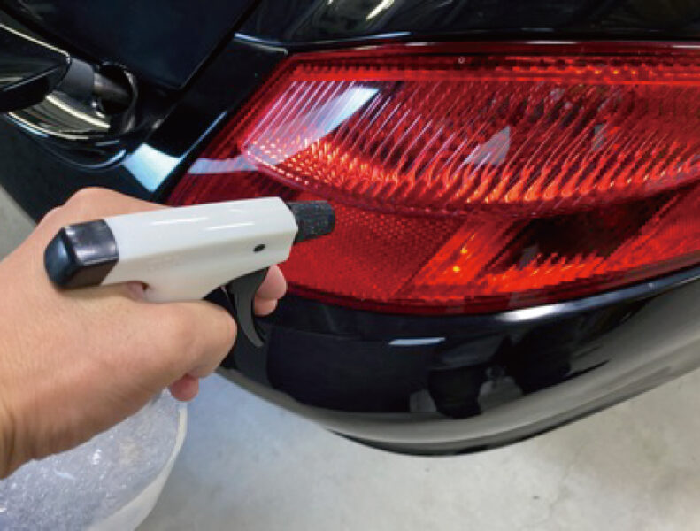 ラッピングする前にテールライトに霧吹きで水をかける様子