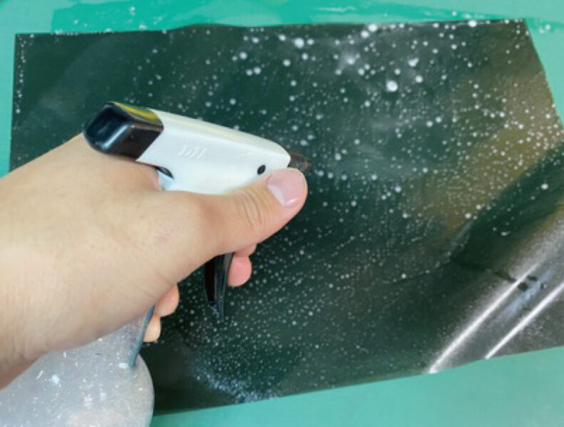 スモークフィルムをラッピングする間に霧吹きで水をかける様子