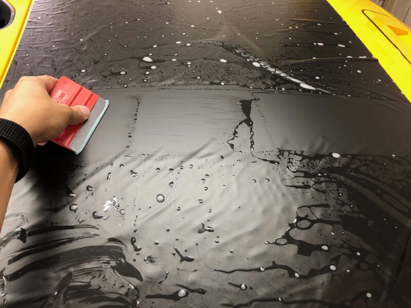 fjクルーザーのボンネットデカールの施工中の様子
スキージで水を抜く様子