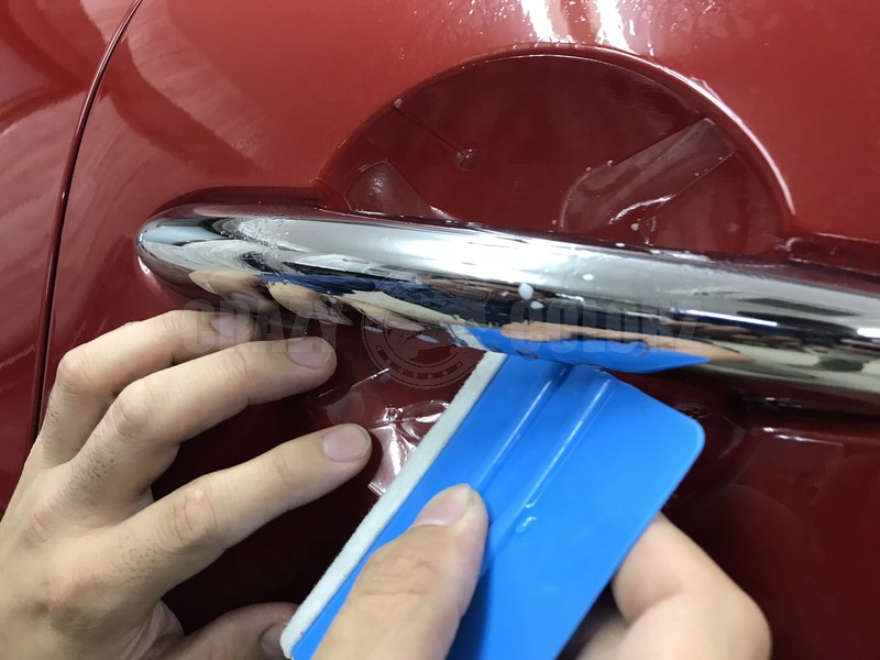 ドアノブプロテクションをスキージで貼っている様子