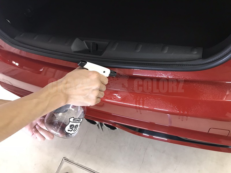 MINI Cooper Sのリアバンパープロテクション施工前に水溶液を吹き付けている様子