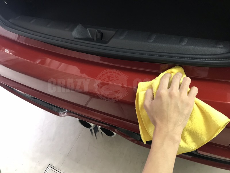 MINI Cooper Sのリアバンパープロテクション施工前に貼り付け面をタオルで清掃している様子