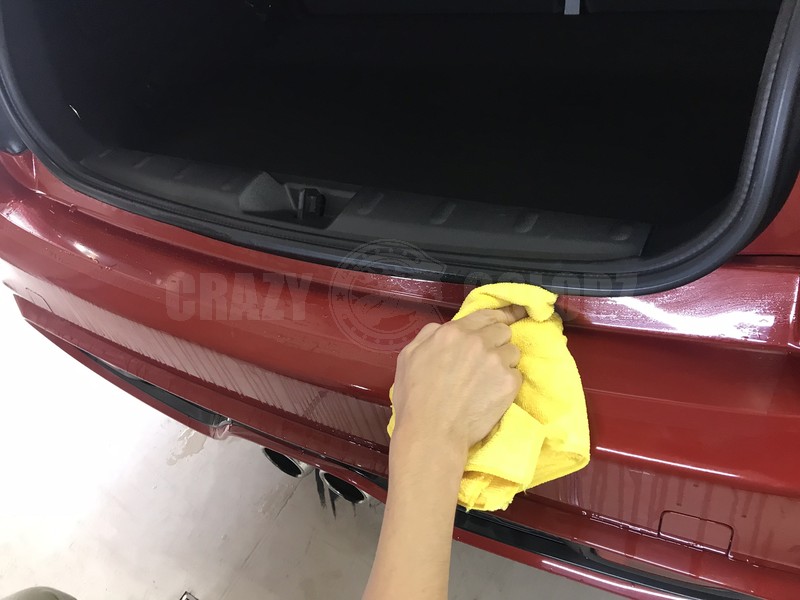MINI Cooper Sのリアバンパープロテクション施工後に水残りをタオルで拭き取っている様子